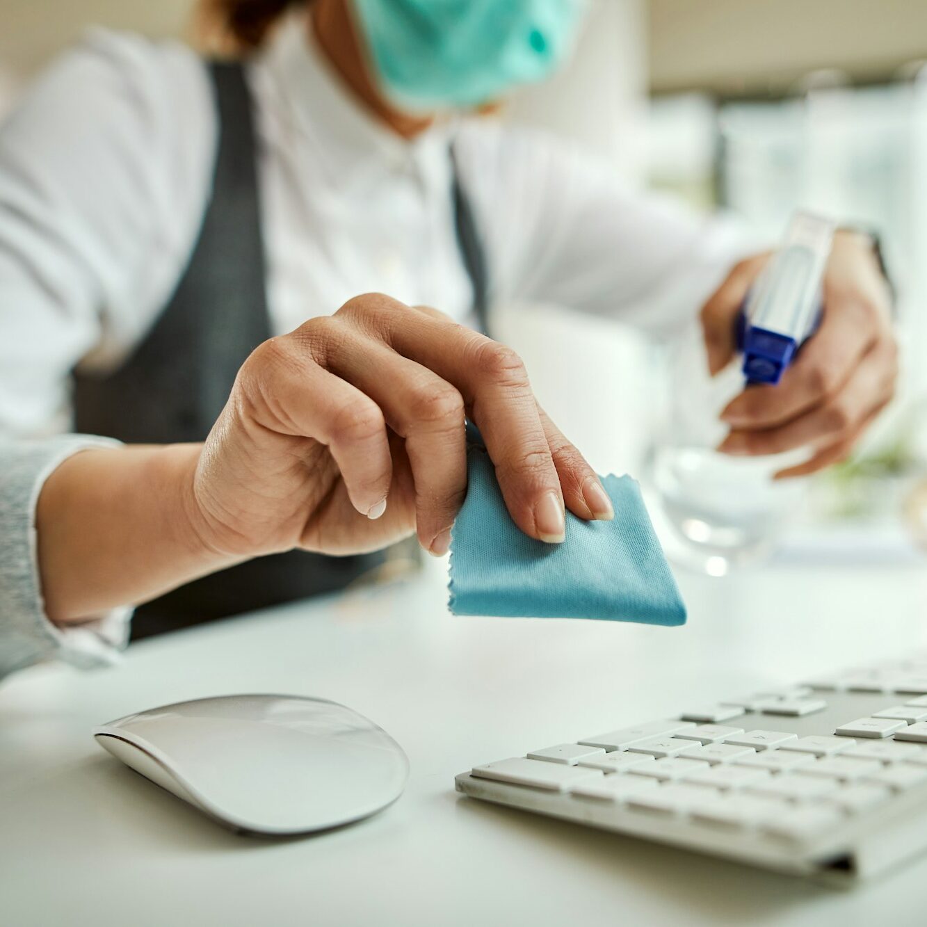 Close-up of businesswoman disinfecting computer keyboard in the office.